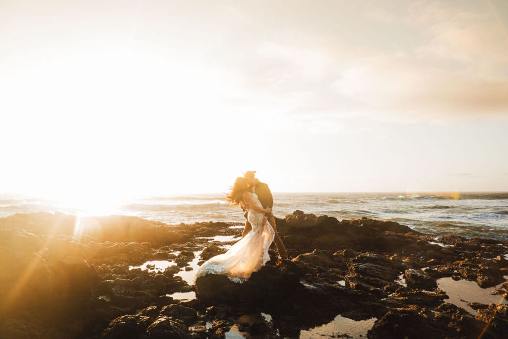 couple eloping on the Oregon coast. They are kissing on a rocky beach